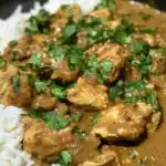 Delicious chicken curry served with white rice, garnished with fresh cilantro, perfect for a flavorful and hearty meal.